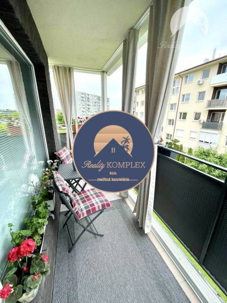 The balcony of a 2-room apartment in Dunajská Streda with garden furniture and flowers.