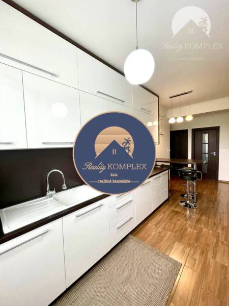 A kitchen in a 2-room apartment with white cabinets and a wood-patterned floor.
