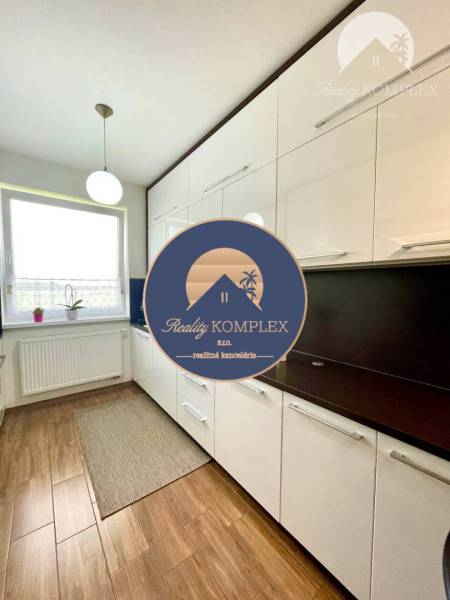 A kitchen in a 2-room apartment with a wood-patterned floor and white furniture.