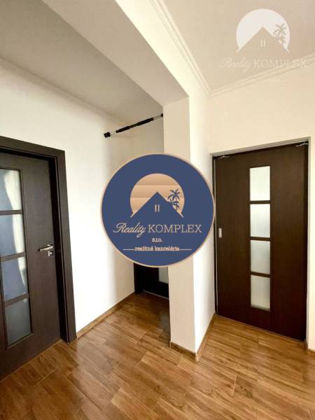 A hallway with built-in wooden doors and a floor with a wooden decor in a 2-room apartment.