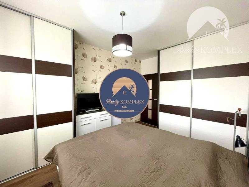 Bedroom in a 2-room apartment with wallpaper, TV, and a large wardrobe.