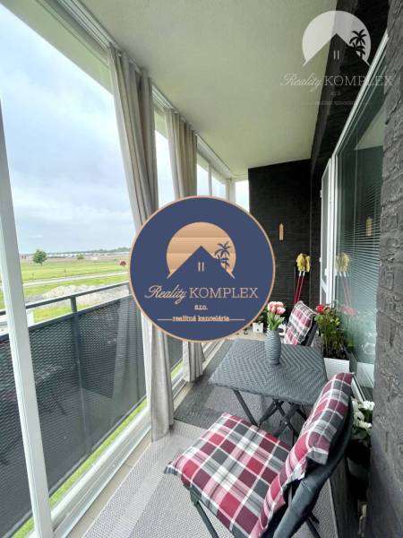 The balcony of a 2-room apartment in Dunajská Streda with a view of greenery and comfortable seating.