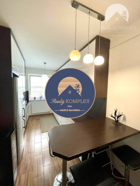 A kitchen in a two-room apartment with a wooden decor floor and a bar table.