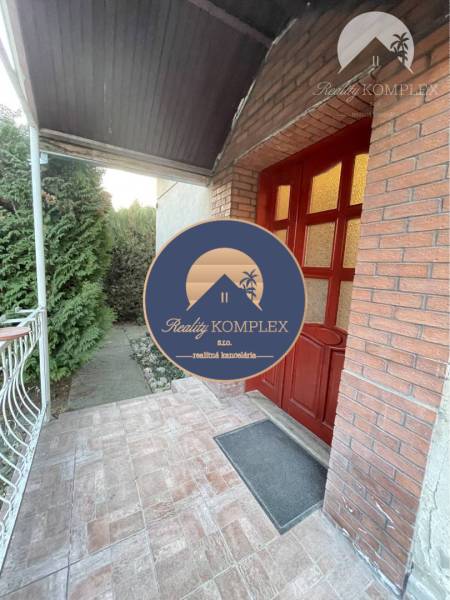 Entrance to a family house in Vrakúň with a covered veranda and a brick wall.