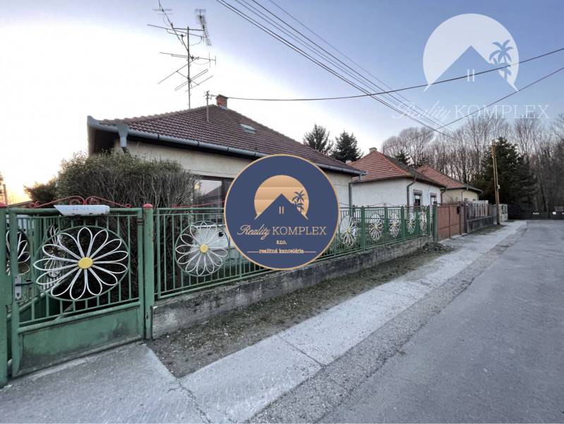 A family house in Vrakúňa with a colorful fence and a satellite dish. A street next to the house.