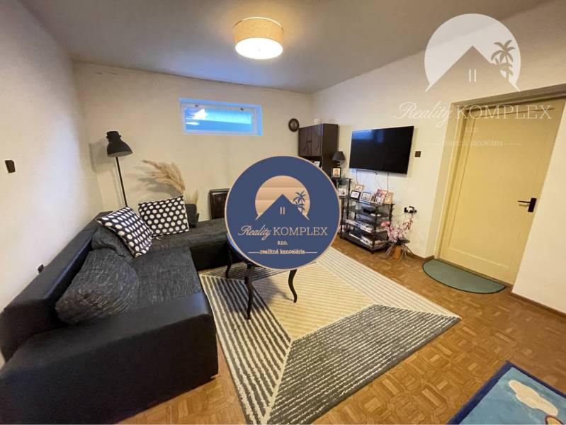 Living room in a family house with a sofa, television, and wooden decor flooring.