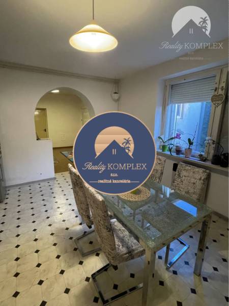 Dining room in a family house; glass table, chairs, window with plants on the windowsill.