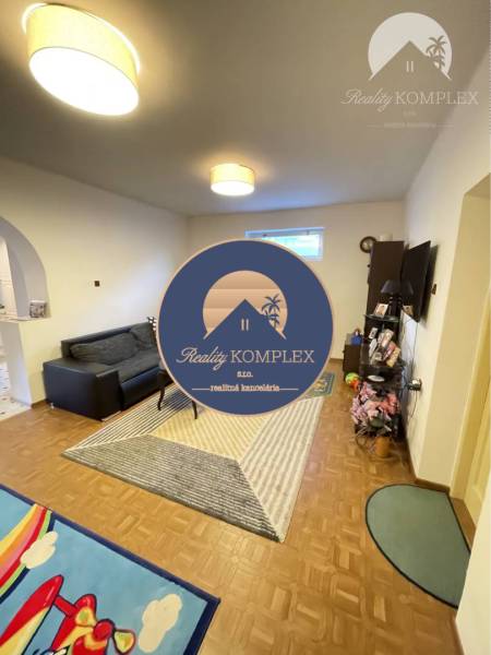 Living room with a sofa and television in a family house with a wooden decor floor.