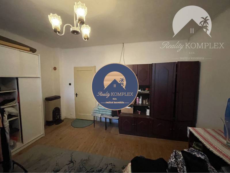 A room in a family house with a wooden decor floor, cabinets, and chandeliers.