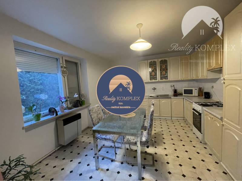A kitchen in a family house with a window, white cabinets, and a dining table.