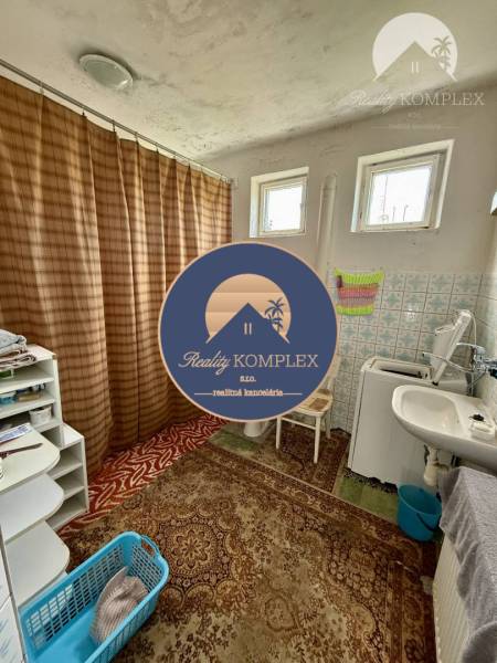 Bathroom in a family house with a bathtub, carpets, and a washing machine.