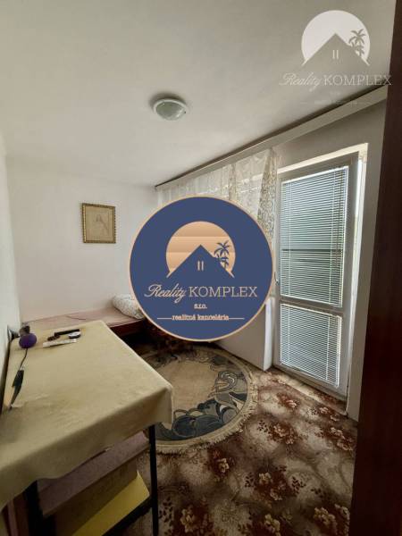 Interior of a family house with a carpet, a table, and a window with curtains.