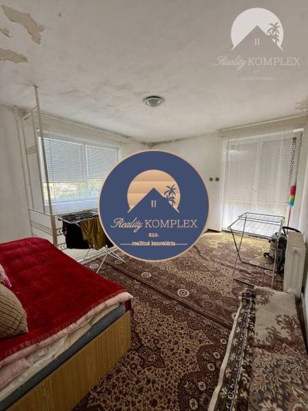 A room in a family house with a carpeted floor, a bed, and a clothes drying rack.