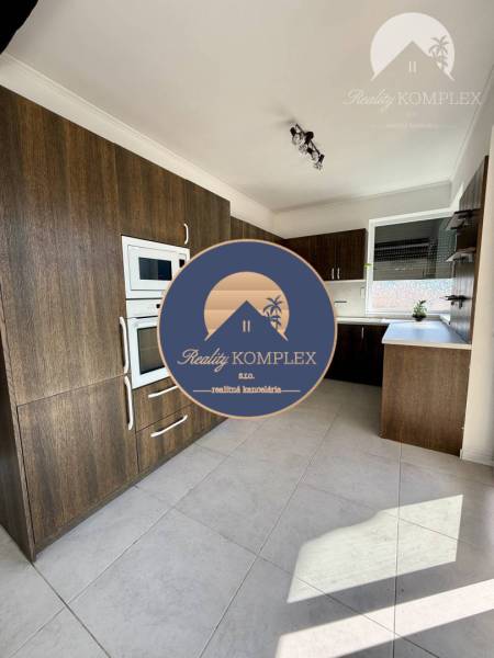 A kitchen with dark cabinets and a light floor in a family house.