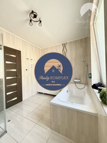 A bathroom in a family house with a bathtub and ceramic tiles.