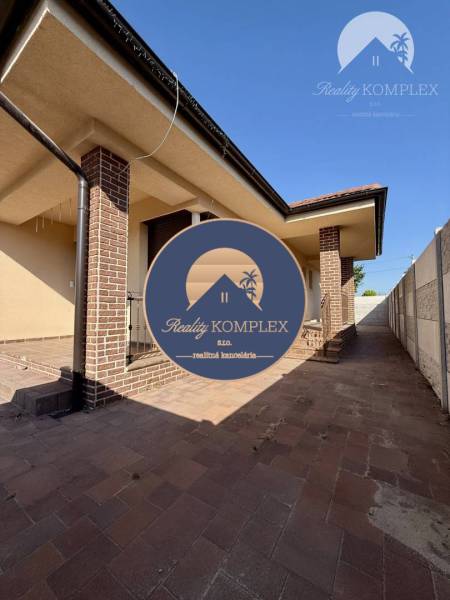 A family house in Okoč with brick details and a paved courtyard.