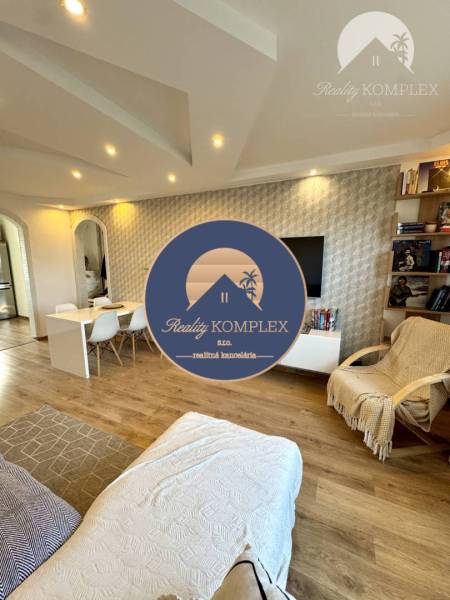 Living room of a 4-room apartment with a sofa, a desk, and shelves with books.