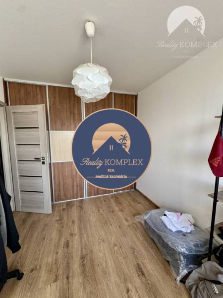 A room in a four-room apartment with wooden flooring, a built-in wardrobe, and a white light fixture.