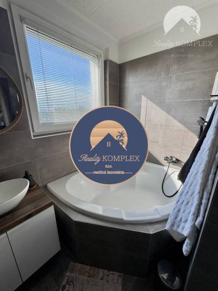 A bathroom corner with a rounded bathtub and a sink in a 4-room apartment.