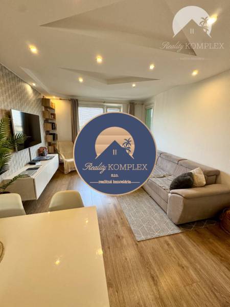 Living room in a 4-room apartment with a comfortable sofa and a TV on the wall.