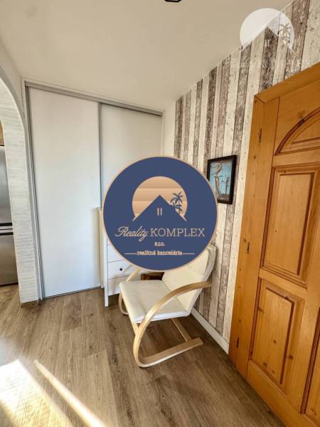 Interior of a 4-room apartment with an armchair, wooden flooring, and modern storage space.