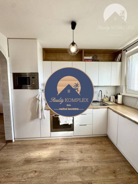 Kitchen in a 4-room apartment with wooden flooring, a light fixture, and built-in appliances.