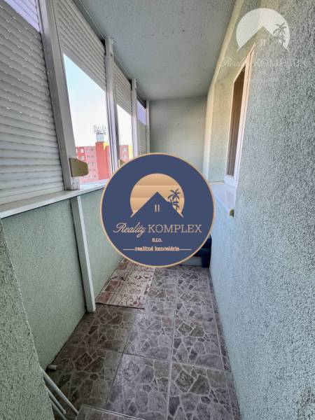 A balcony of a 4-room apartment with tiles and sliding windows in a housing estate.