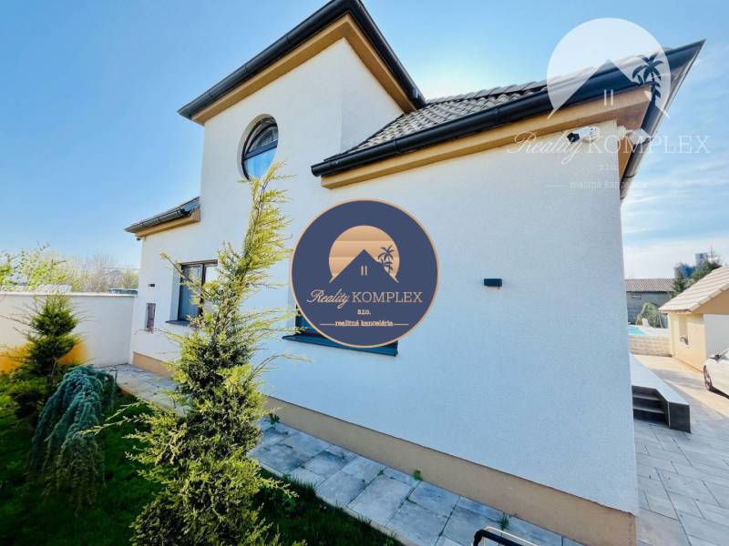 A family house with a side view, a landscaped front garden, and a paved area in the yard.