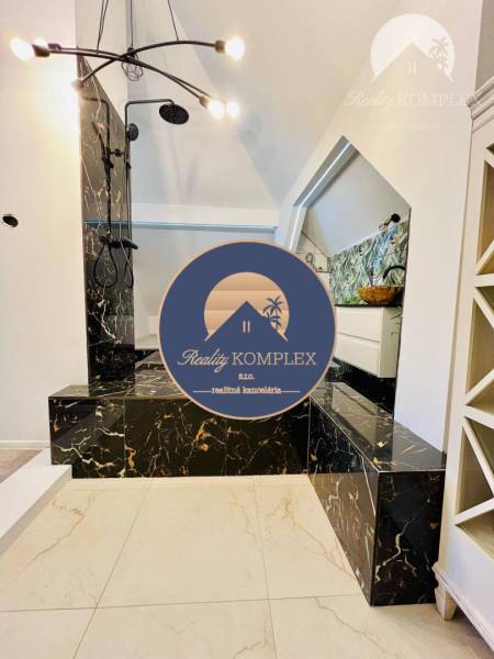 A bathroom with a shower, marble tiles, a stylish light fixture, located in a family house.