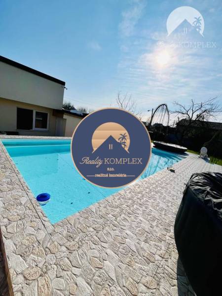 Family house with a pool, stone terrace, and a sunny day in the garden.