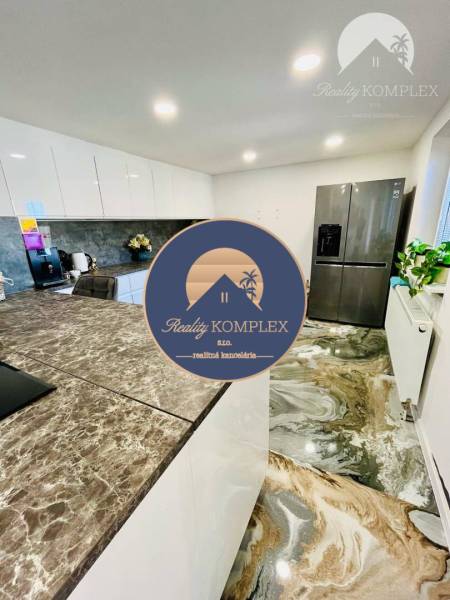 A kitchen in a family house with a marble floor, a bar counter, and a modern kitchen unit.