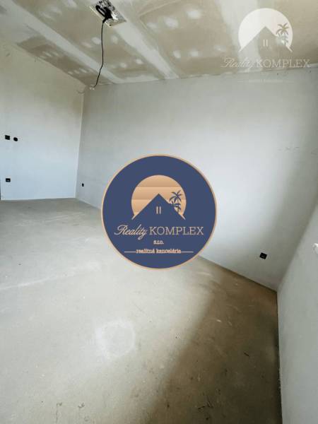 A room in a 3-room apartment with white walls and prepared ceiling wiring.