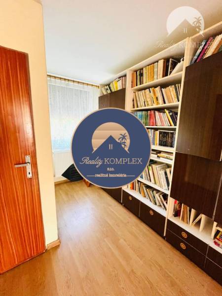 A room with bookshelves, a floor with a wooden decor, a door to the room.