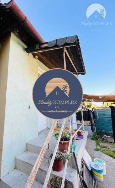 A family house in Okoč with an outdoor staircase and potted plants.