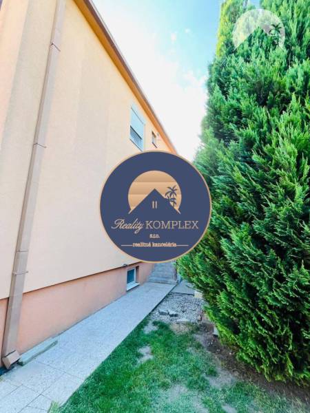 A family house in Okoč surrounded by a narrow path and dense trees.