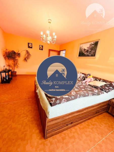 A room in a family house with orange walls, a wood-patterned floor, and a chandelier.