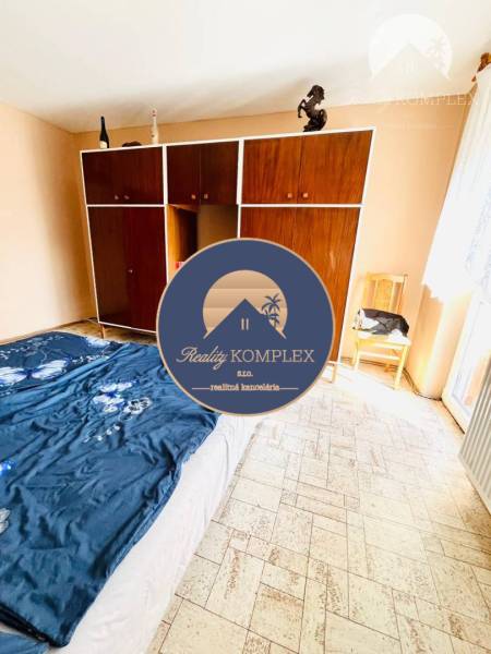 A bedroom in a family house with a large wardrobe and patterned floor.