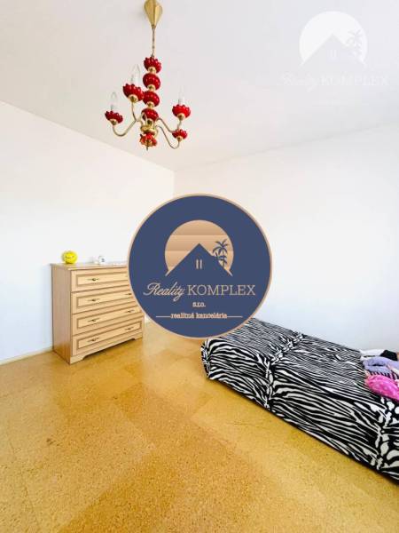 Interior of a family house with a bed, dresser, and chandelier, floor with wood decor.