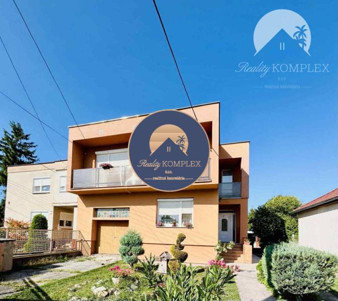 A family house in Okoč with a garden and a balcony under the blue sky.