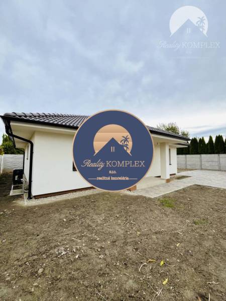 A family house in Topoľníky with a sloped roof and a paved walkway in the yard.