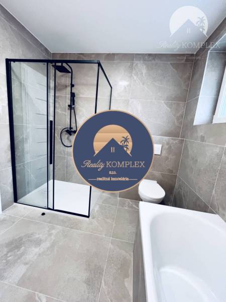 A family house bathroom with large-format tiles, a shower corner, and a bathtub.
