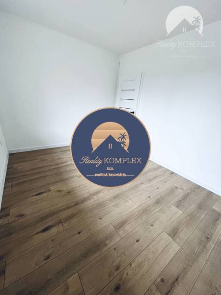 A room in a family house with white walls and a wooden decor floor.