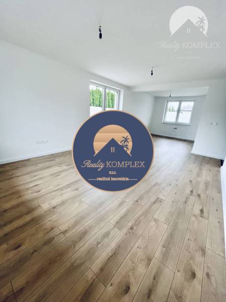 Living room in a family house with wood-patterned flooring and large windows.