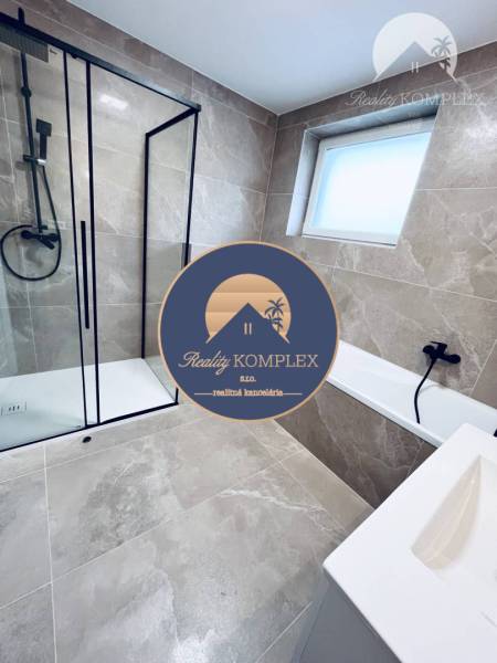 A bathroom in a family house with a glass-enclosed shower and light tiles.