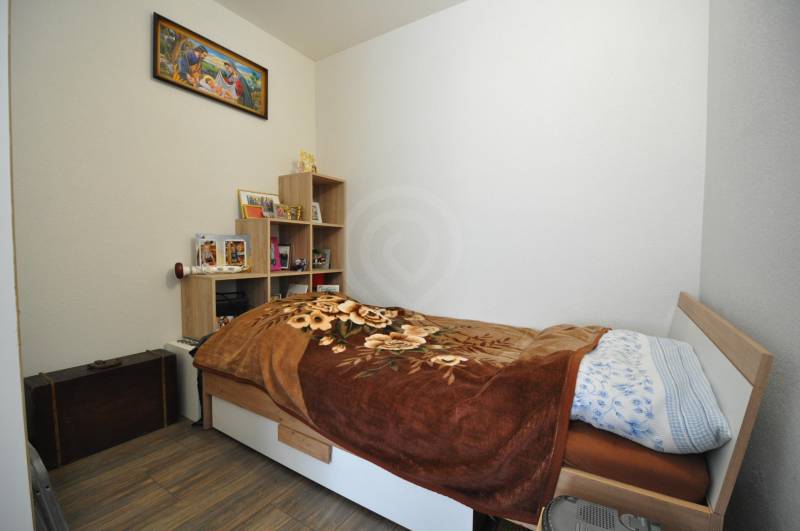 Simple bedroom with a bed, shelves, and decorations in a 2-room apartment.