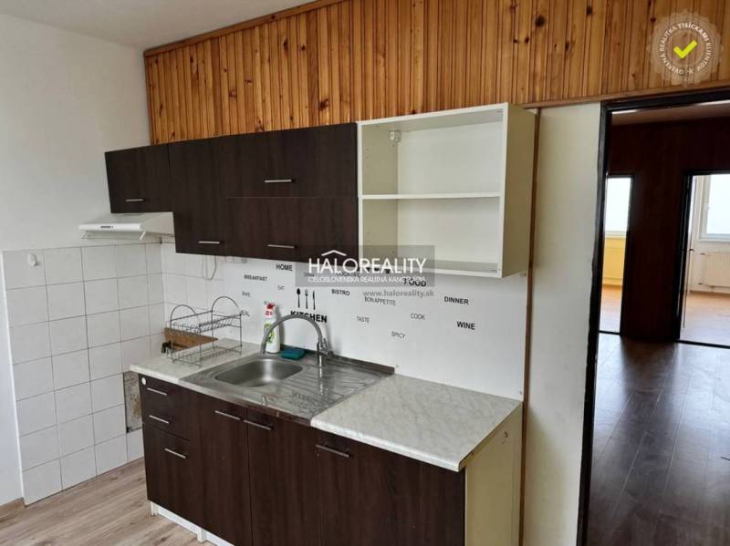A kitchen in a 4-room apartment with white and dark cabinets, and a floor with a wood decor.