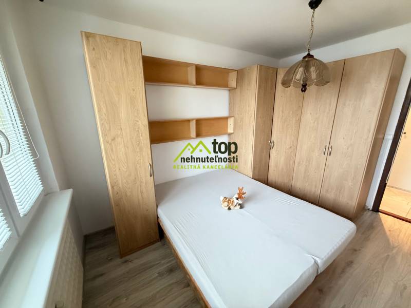 Bedroom with a bed and cabinets in a 2-room apartment, floor with wood decor.