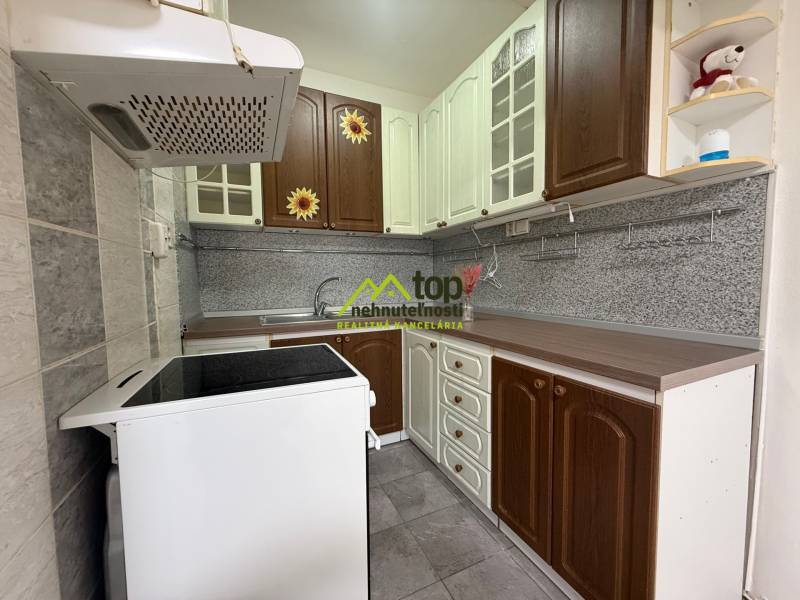 A kitchen in a 2-room apartment with dark brown and white cabinets and a stainless steel countertop.