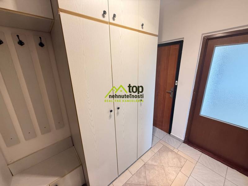 Entrance hall in a 2-room apartment with wardrobes and hangers, floor with wooden decor.