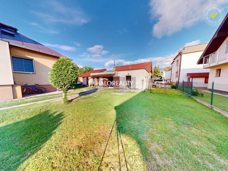 A garden at a family house in Krasňany with a lawn and a tree next to the building.